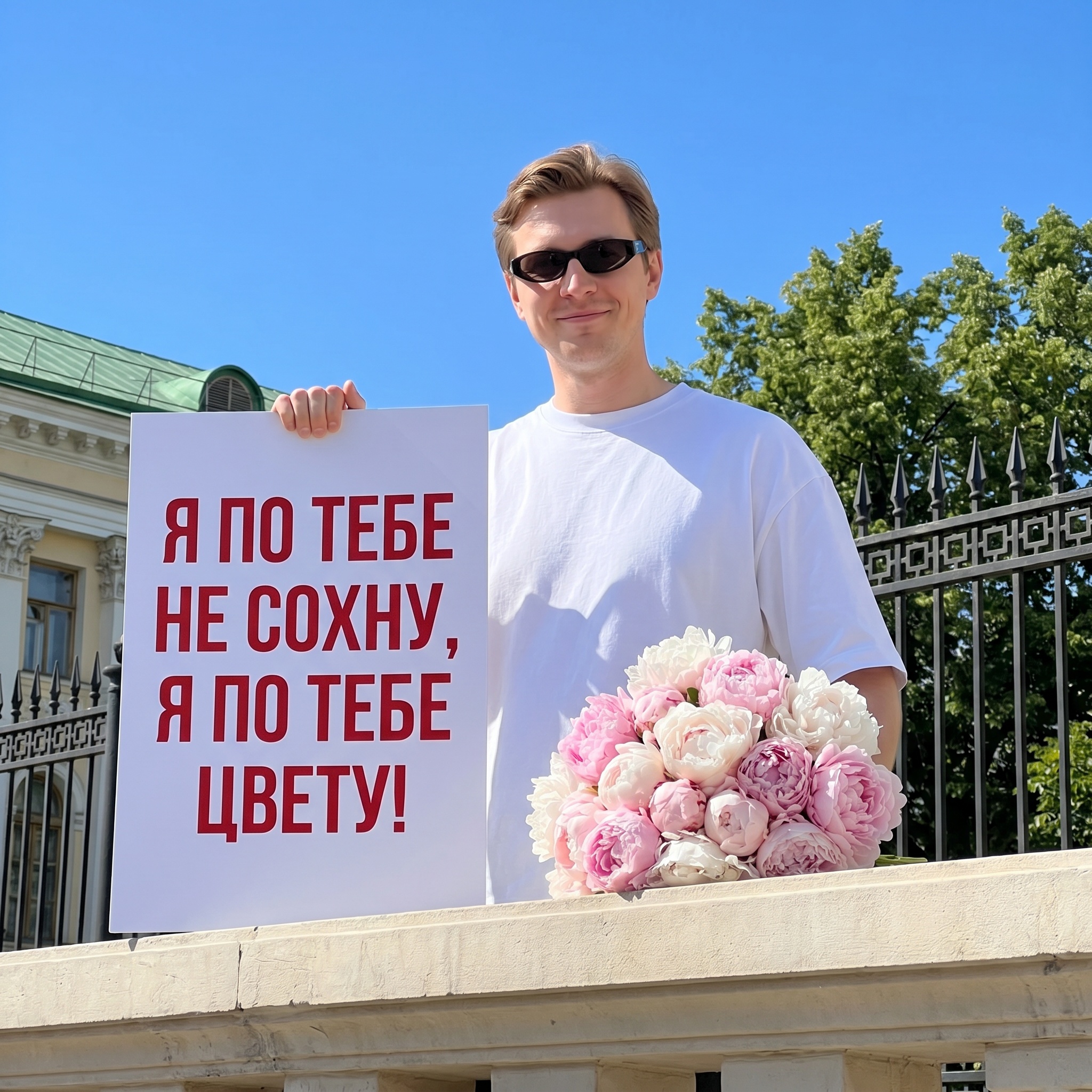 Парень с плакатом и пионами на фоне неба